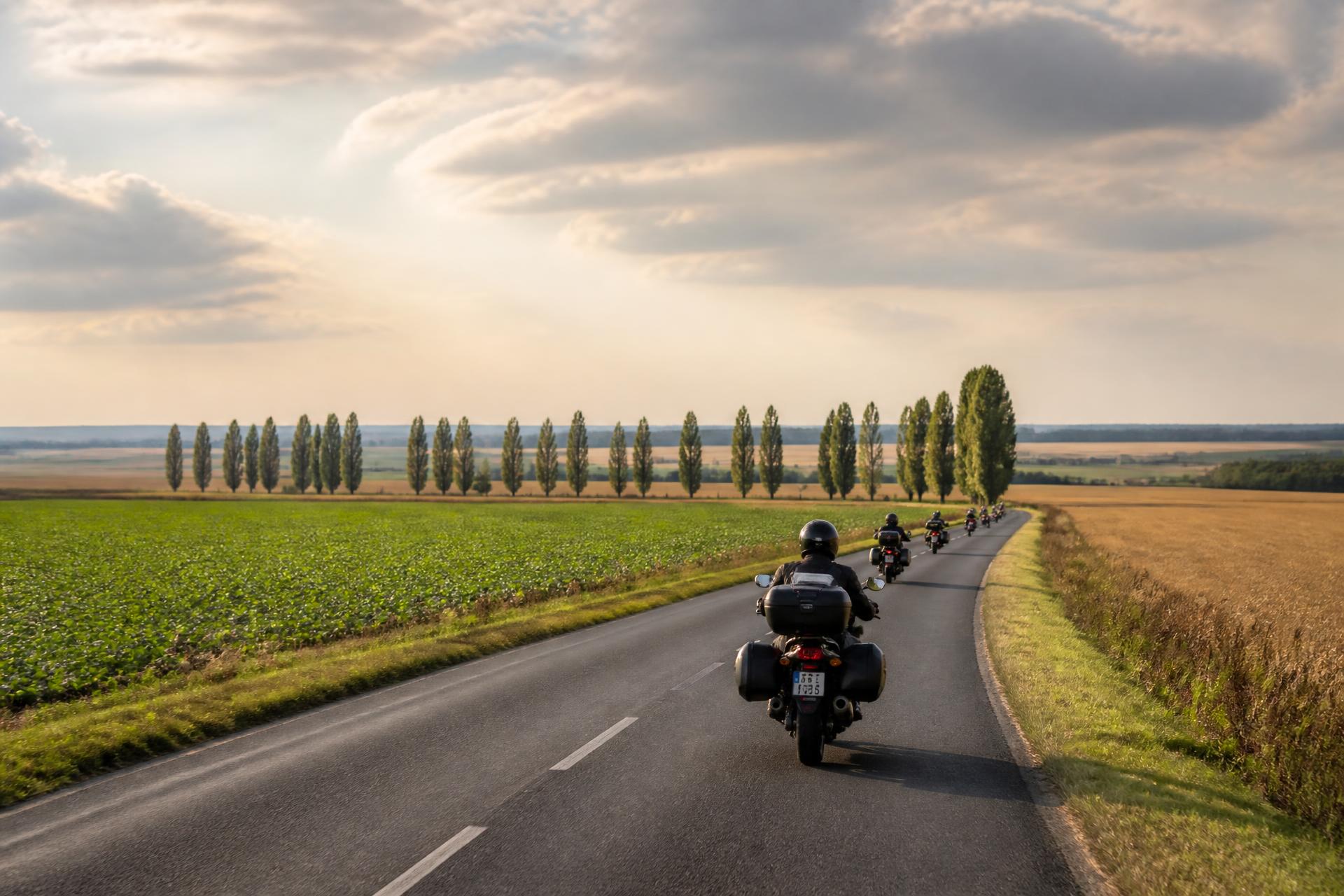 Motards sur une route de plaine agricole de l’Aisne, entre champs et peupliers